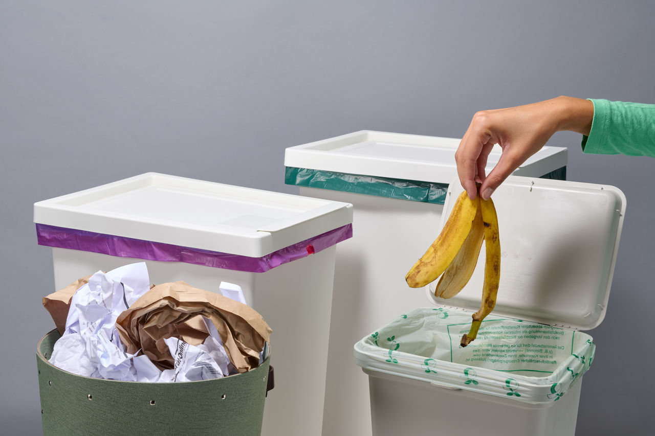 Vier verschiedene Mülleimer und Müllarten, Hand entsorgt Bananenschale in den Biomüll